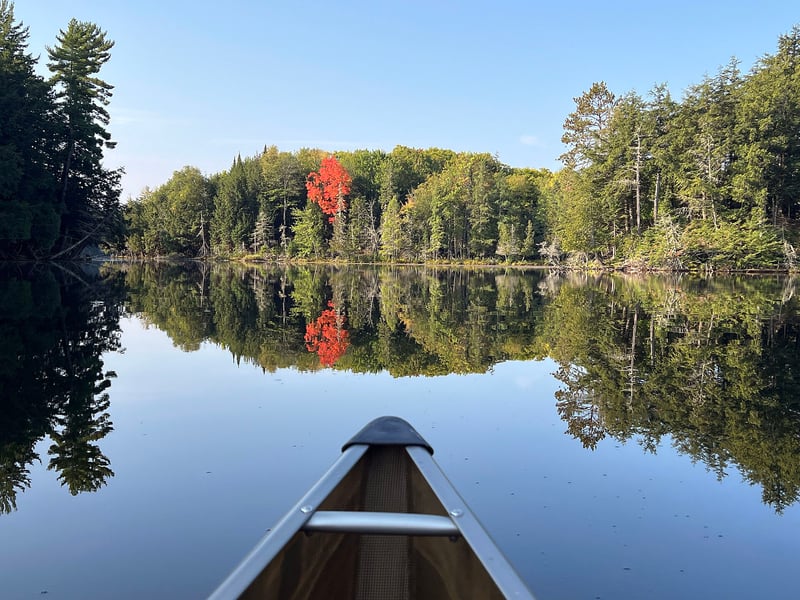 Canoe bow on Crooked Lake in the Sylvania Wilderness, framed by red autumn maples