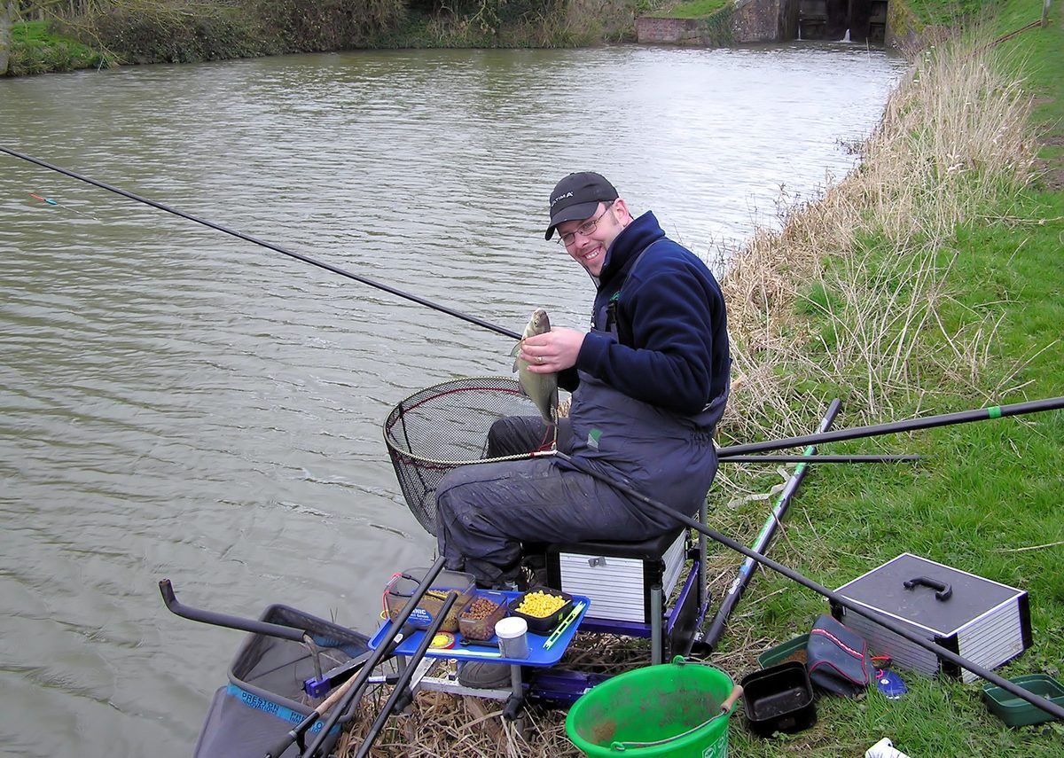 Bank angler fishing a still canal at dusk