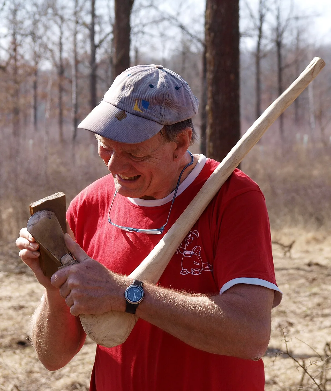 Person hand-sharpening the bit of an axe outdoors
