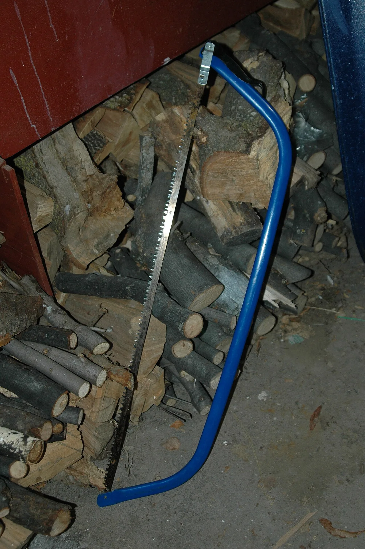 Bow saw resting against a stack of split firewood