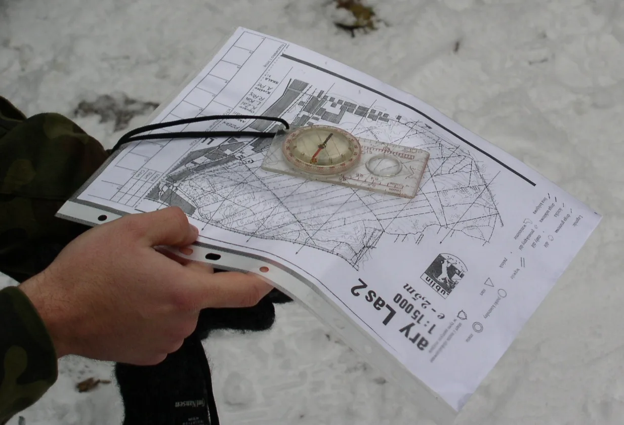 Hand holding an orienteering map with a baseplate compass